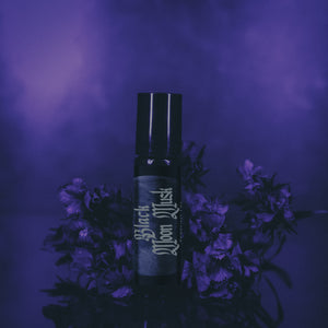 Perfume bottle labeled 'Black Moon Musk' surrounded by flowers on a purple background
