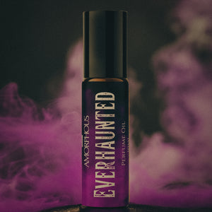 Perfume oil bottle labeled 'Ever Haunted' by Amorphous with purple smoke in the background