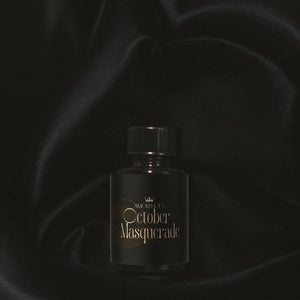 Perfume bottle labeled 'October Masquerade' on a dark background