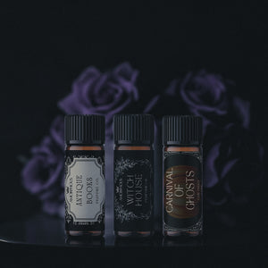 Three small bottles with labels against a dark background with purple roses.